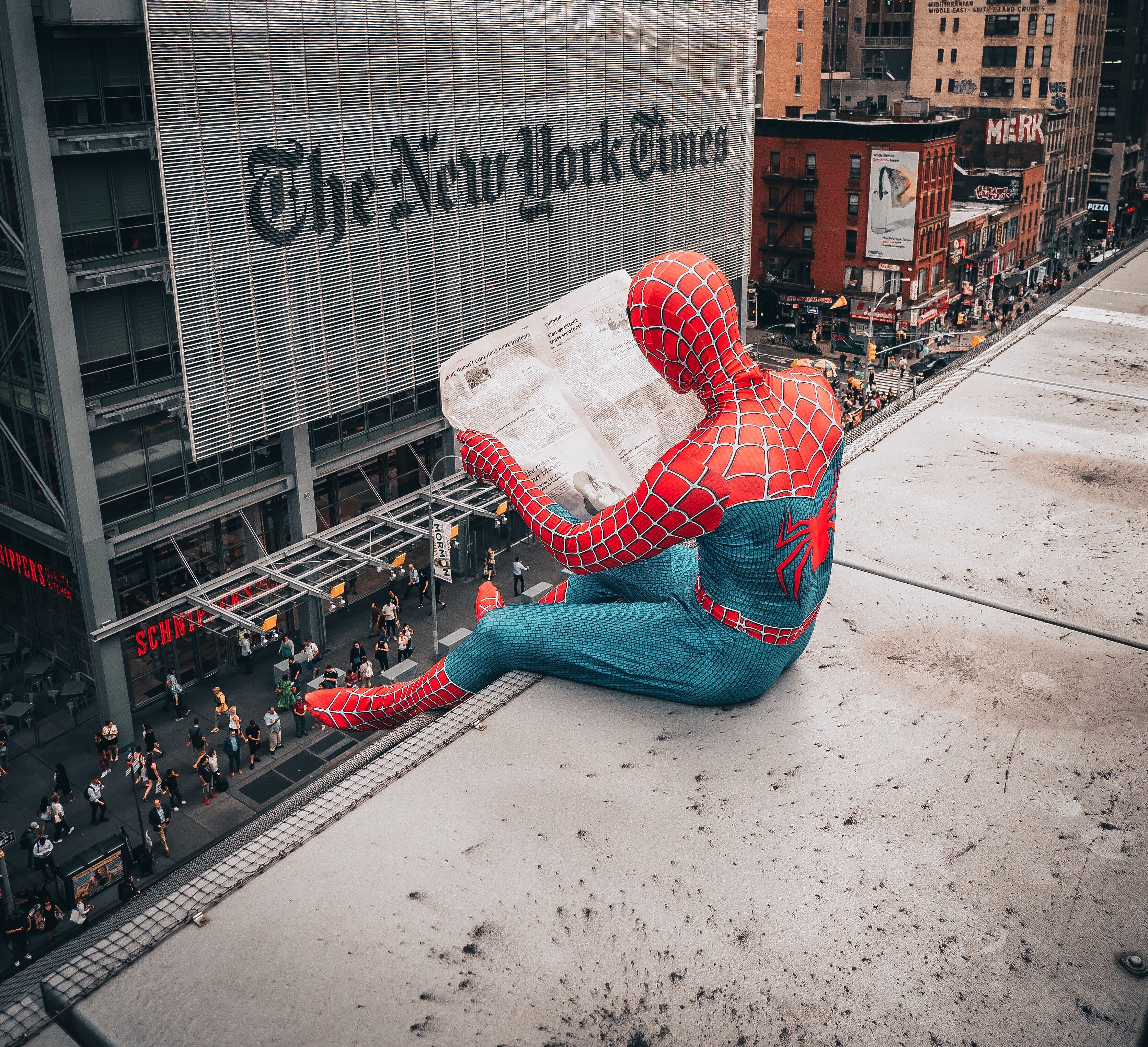 Spiderman sitzt auf Gebäude und liest New York Times