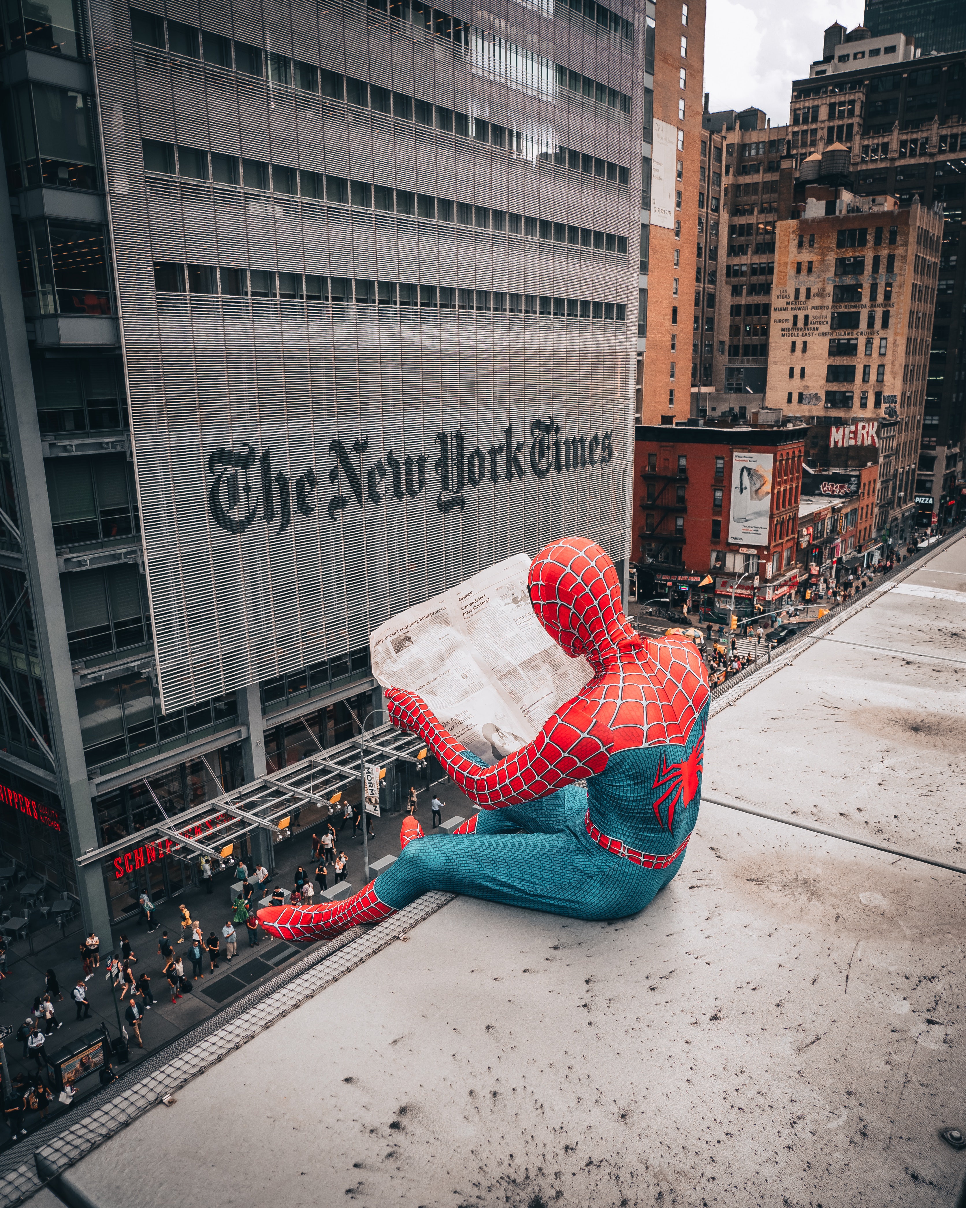 Spiderman sitzt auf Gebäude und liest New York Times